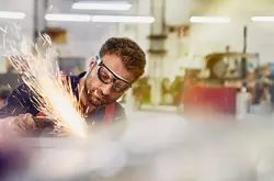 male wearing safety glasses, grinding metal
