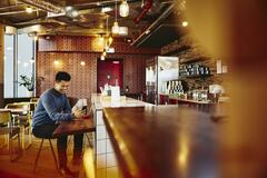 Man sitting in a restaurant smiling and holding is phone.