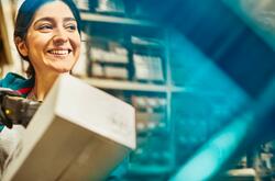 Smiling woman looking away while scanning a package in a warehouse