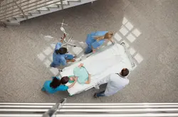 Arial view of nurses and one doctor pushing one patient in a bed in hospital corridor.