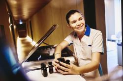 Woman in housekeeping uniform, holding small toiletries bottles.