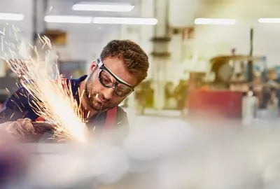 male wearing safety glasses, grinding metal
