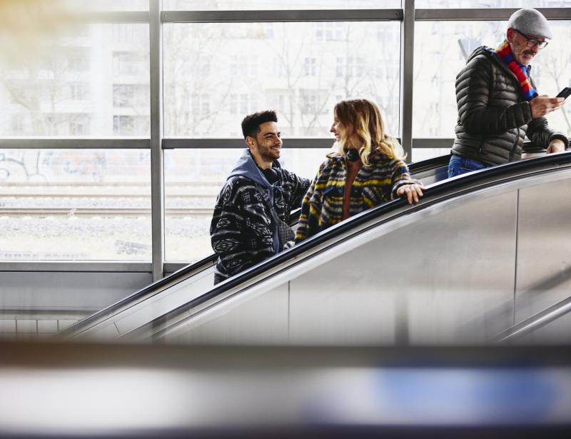 Smiling people on a escalator in a train station.