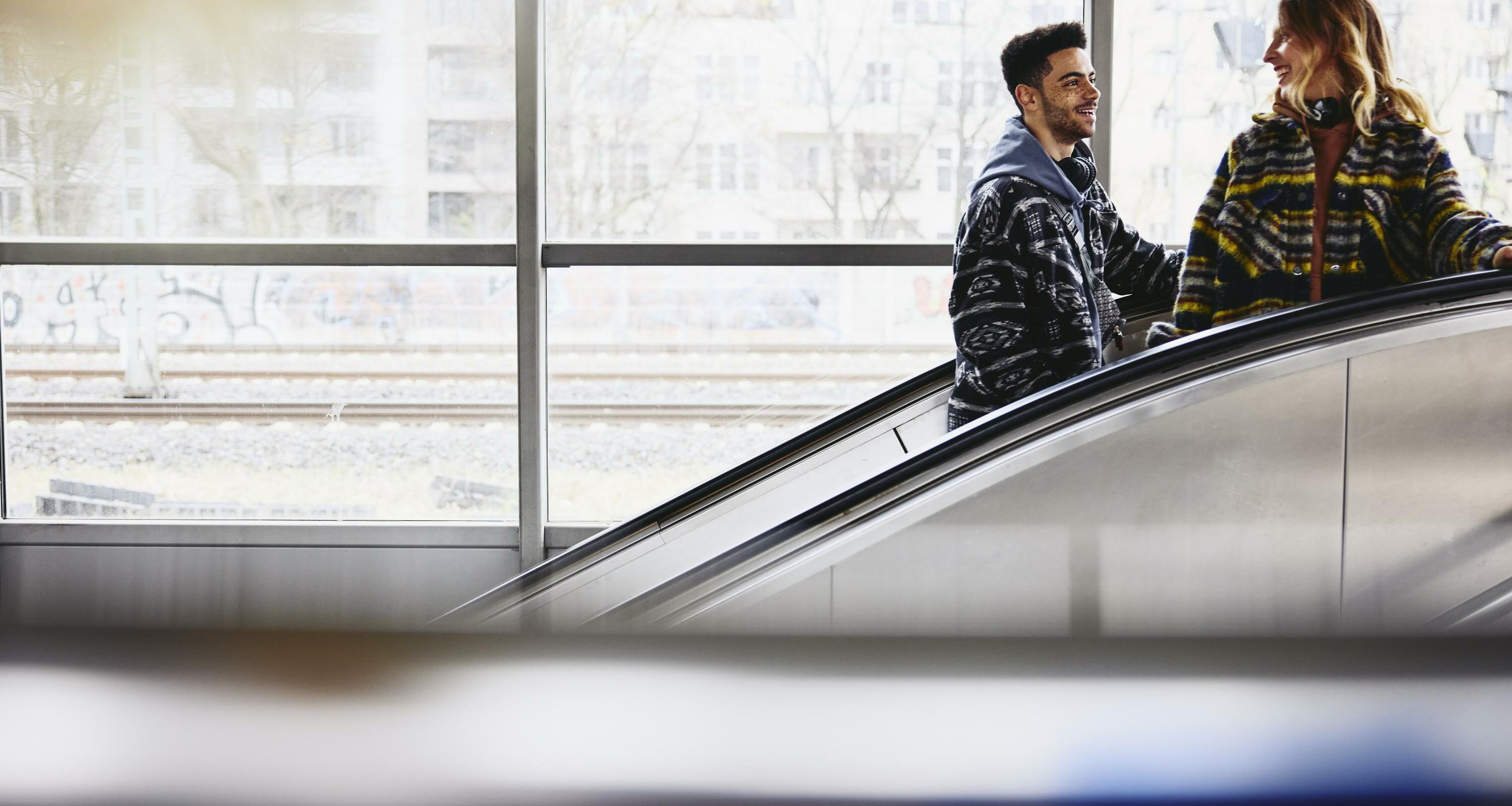 Smiling people on a escalator in a train station.