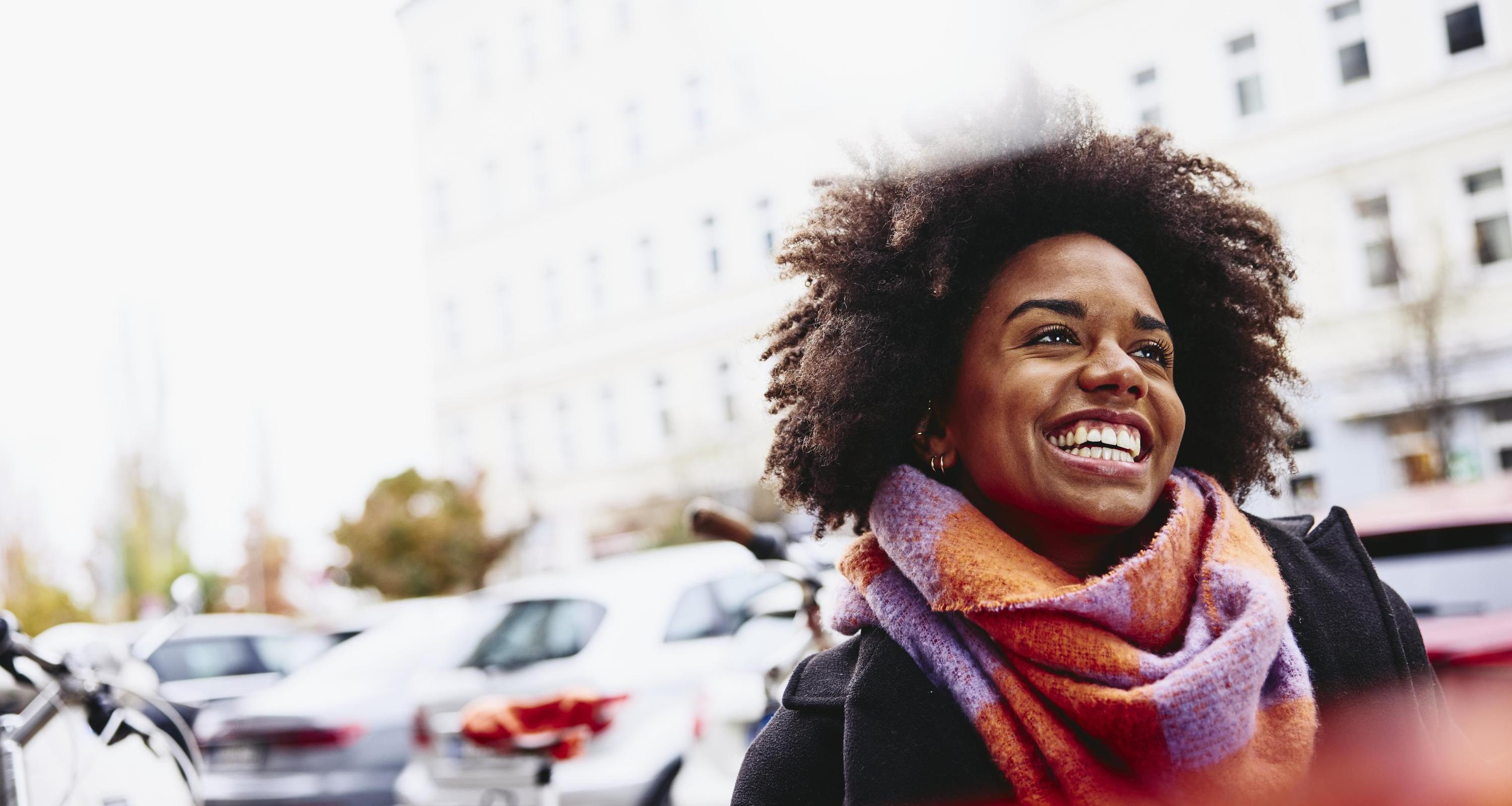 Smiling woman looking up while walking outside.