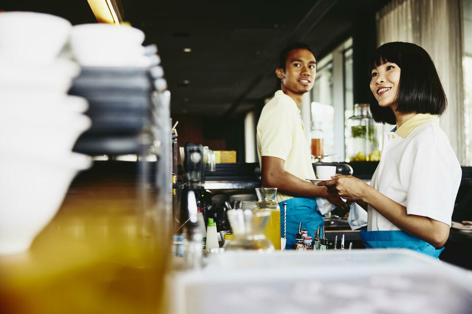 male and female bar tending. Womale holding acoffee cup.
